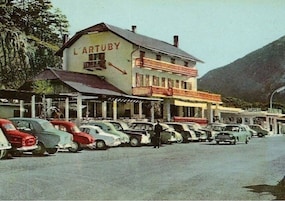 Un edificio con la leyenda 'L'ARTUBY' y una fila de coches aparcados en la parte delantera.