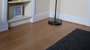Une pièce avec une bibliothèque remplie de livres et d’objets décoratifs, un lampadaire et un plancher en bois.