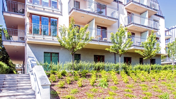 A multi-story residential building with balconies, a staircase, and a landscaped garden area.