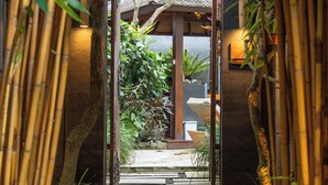 A bamboo archway leading to a garden with a stone pathway and steps. - La Paradis Villa (Pererenan)