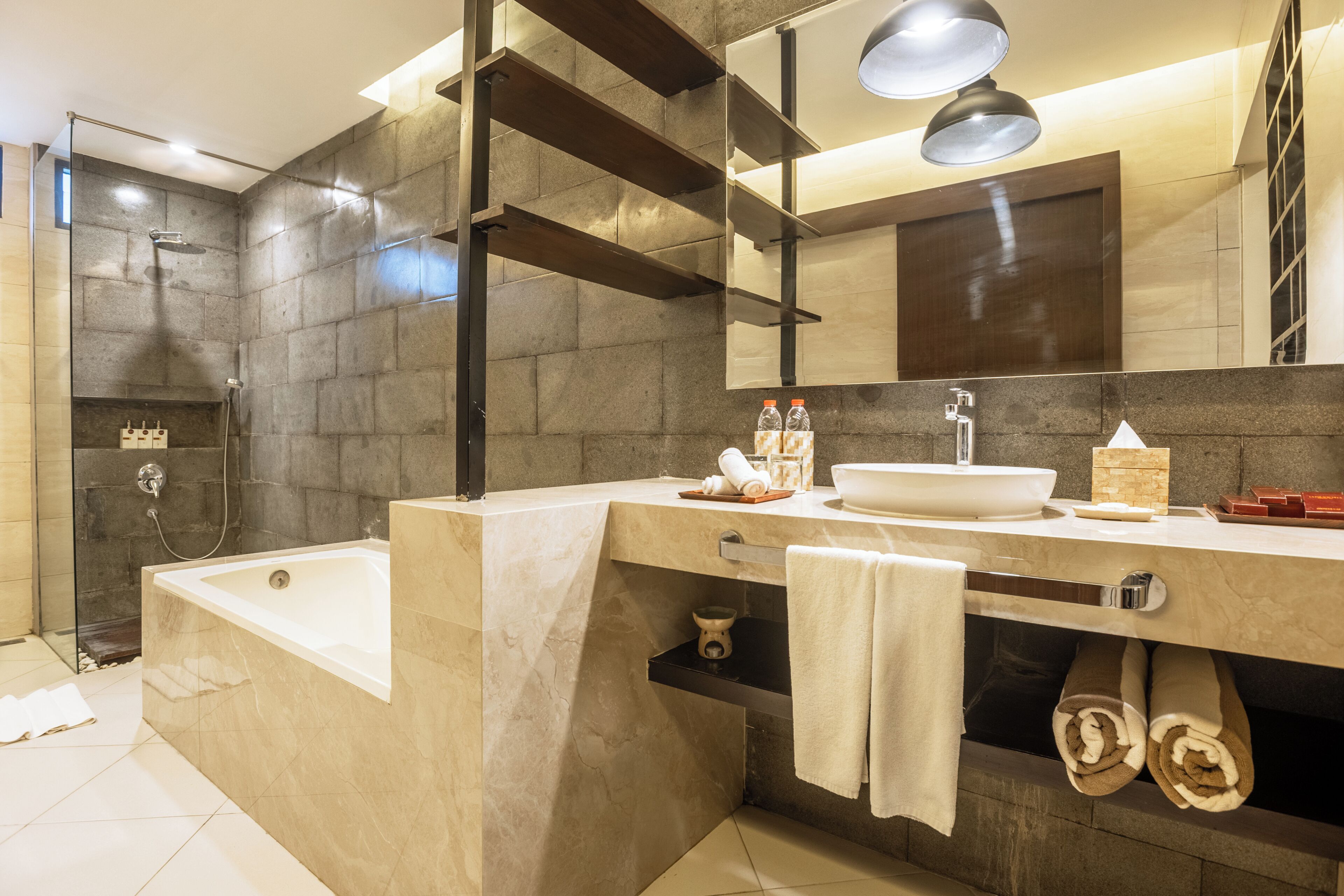 A modern bathroom with a bathtub, a large mirror, a sink, and a shower area.