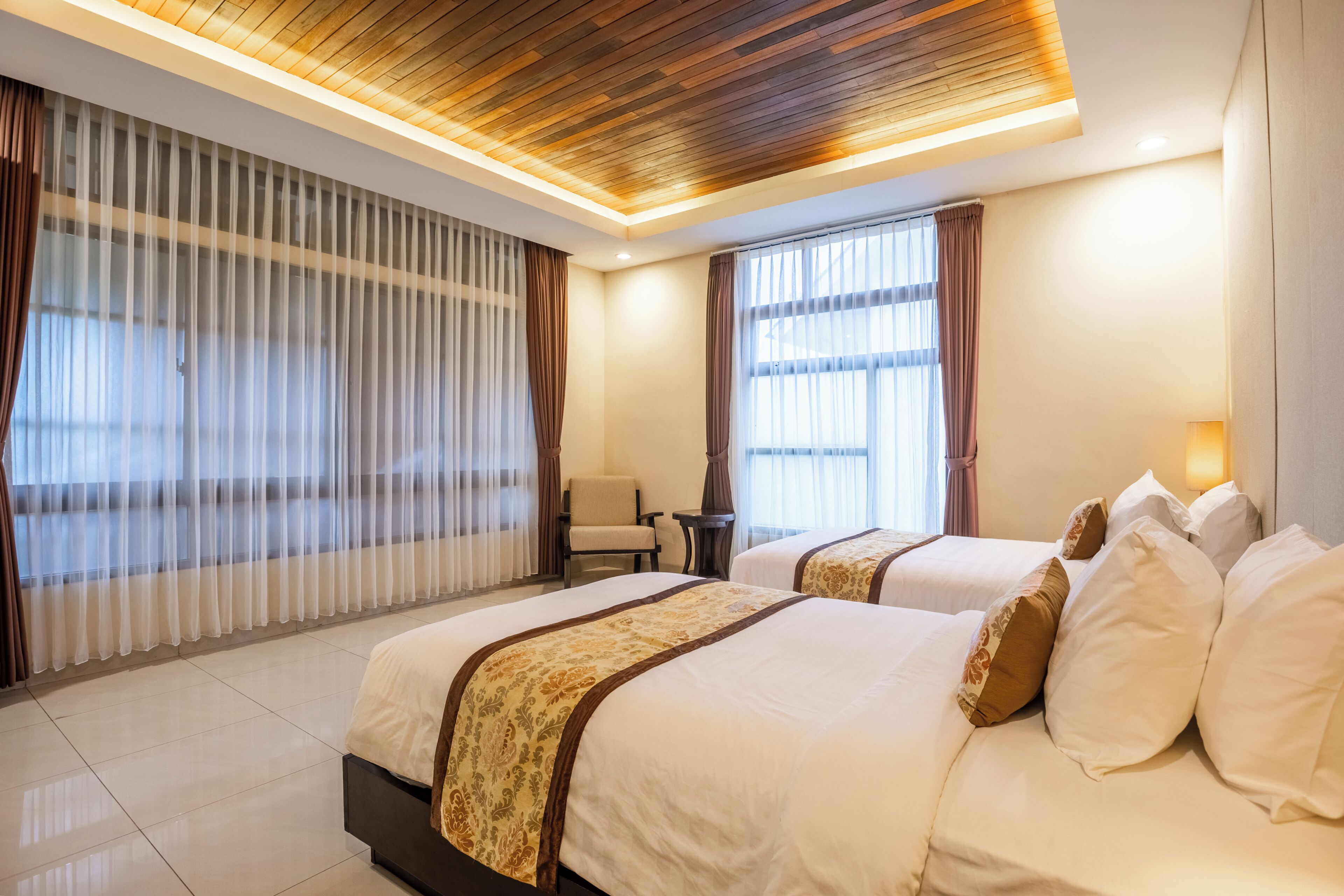 Une chambre d’hôtel avec deux lits, un bureau et une chaise.