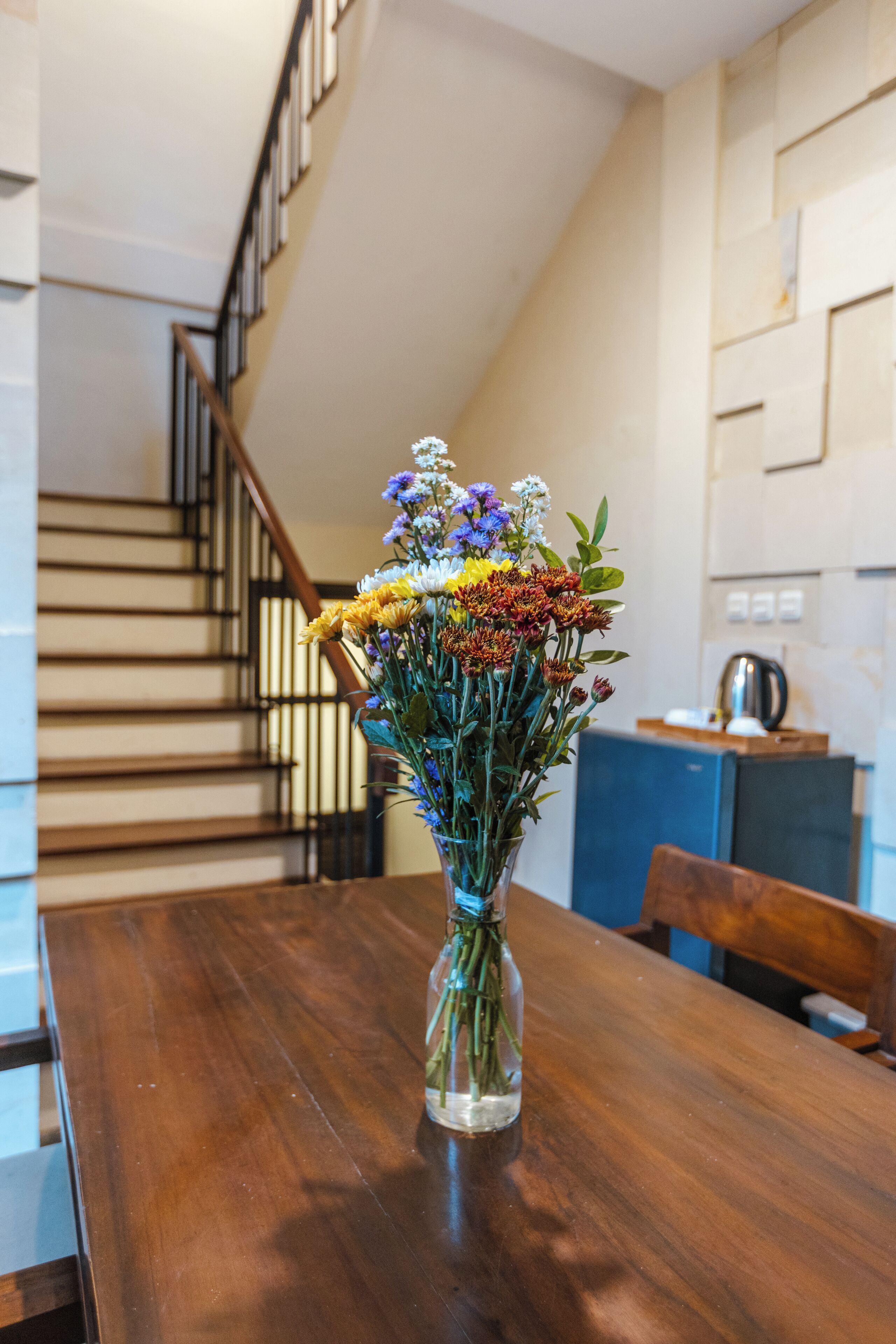 A wooden table with a clear glass vase containing a bouquet of flowers.
