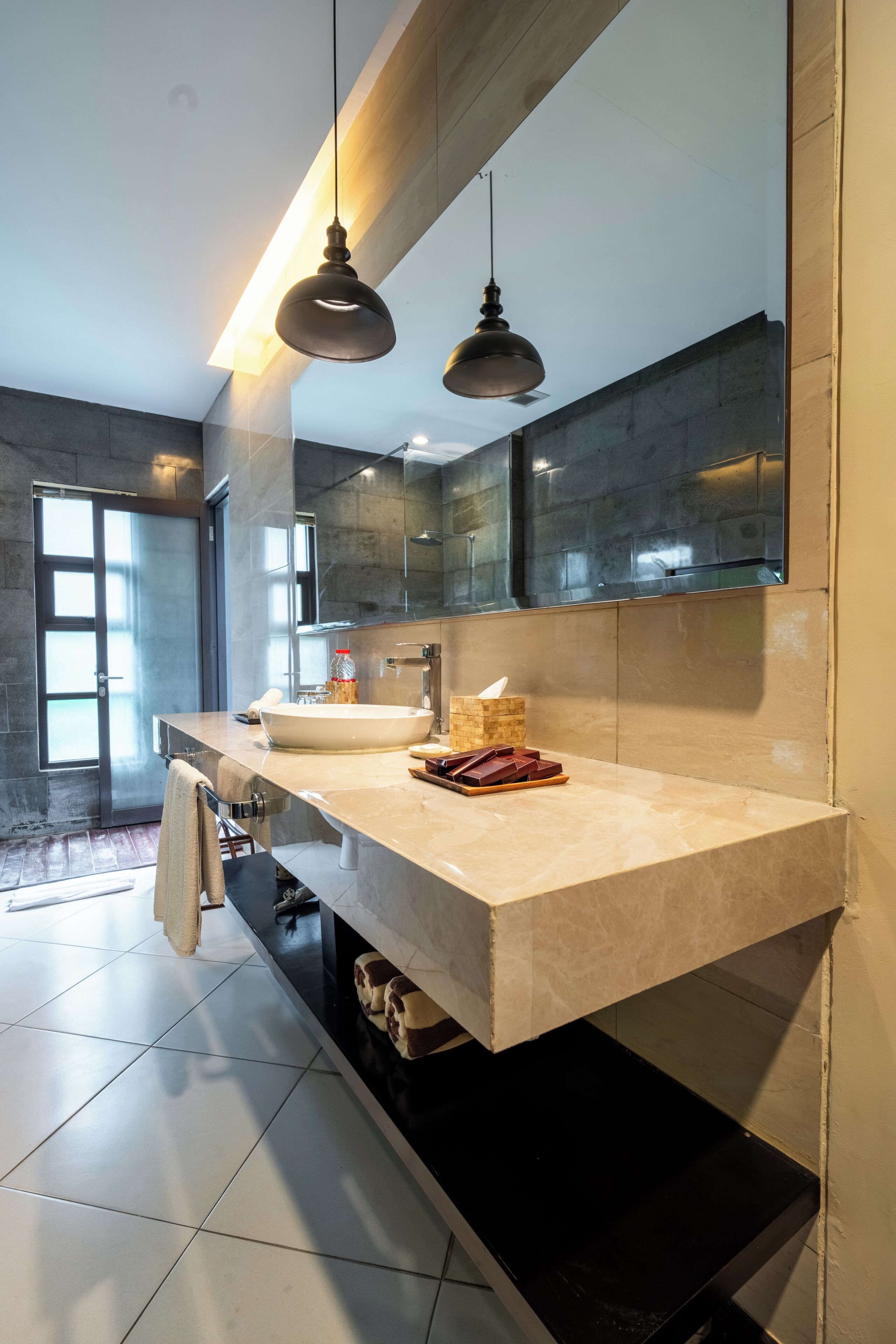 A modern bathroom with a large mirror, a double sink, and a towel rack.