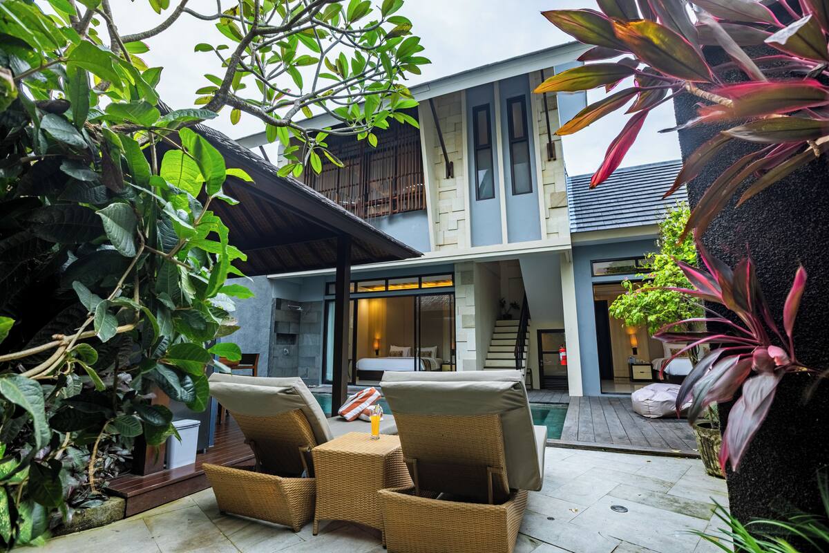 A modern house with a pool, outdoor seating, and lush greenery.