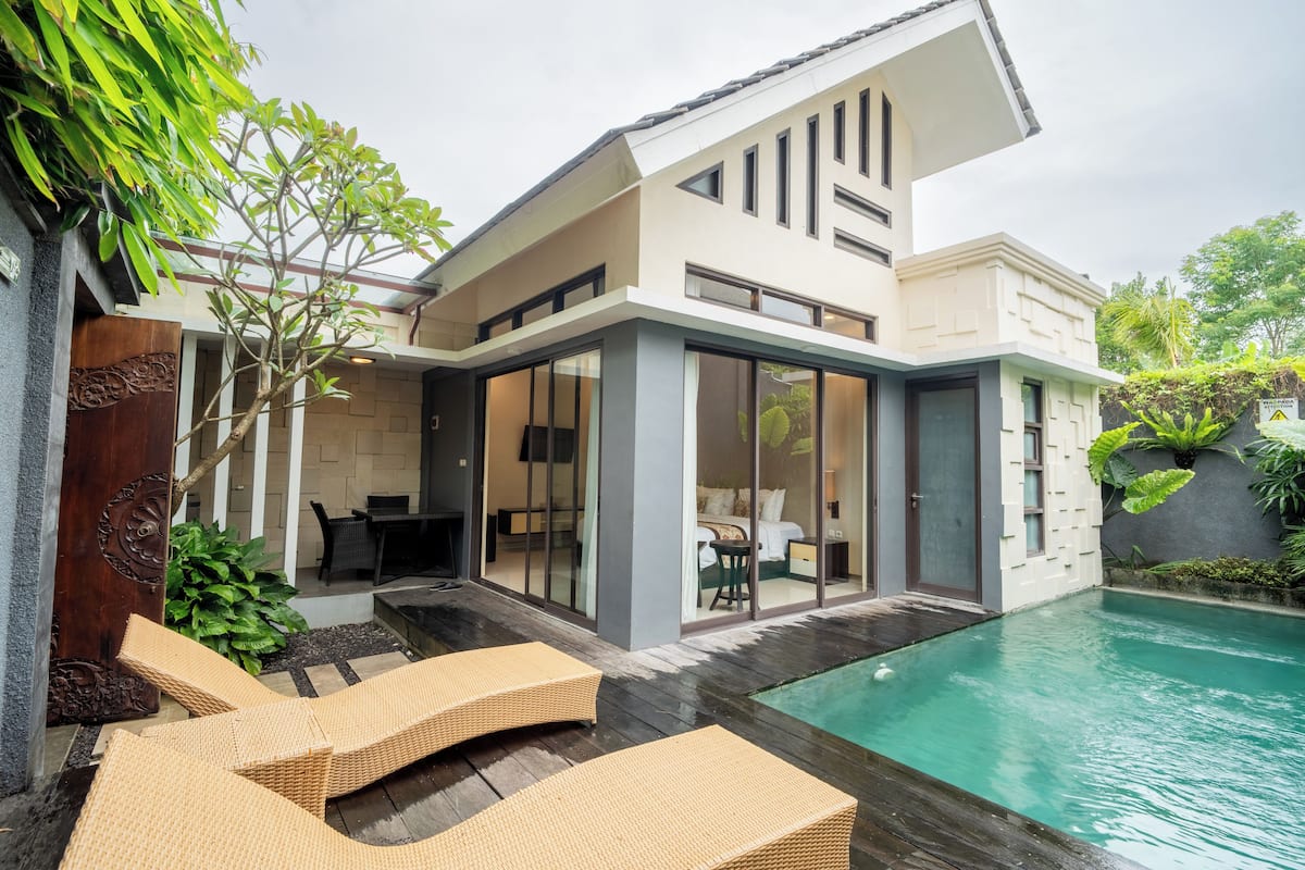 A modern house with a pool, outdoor seating, and a dining area.