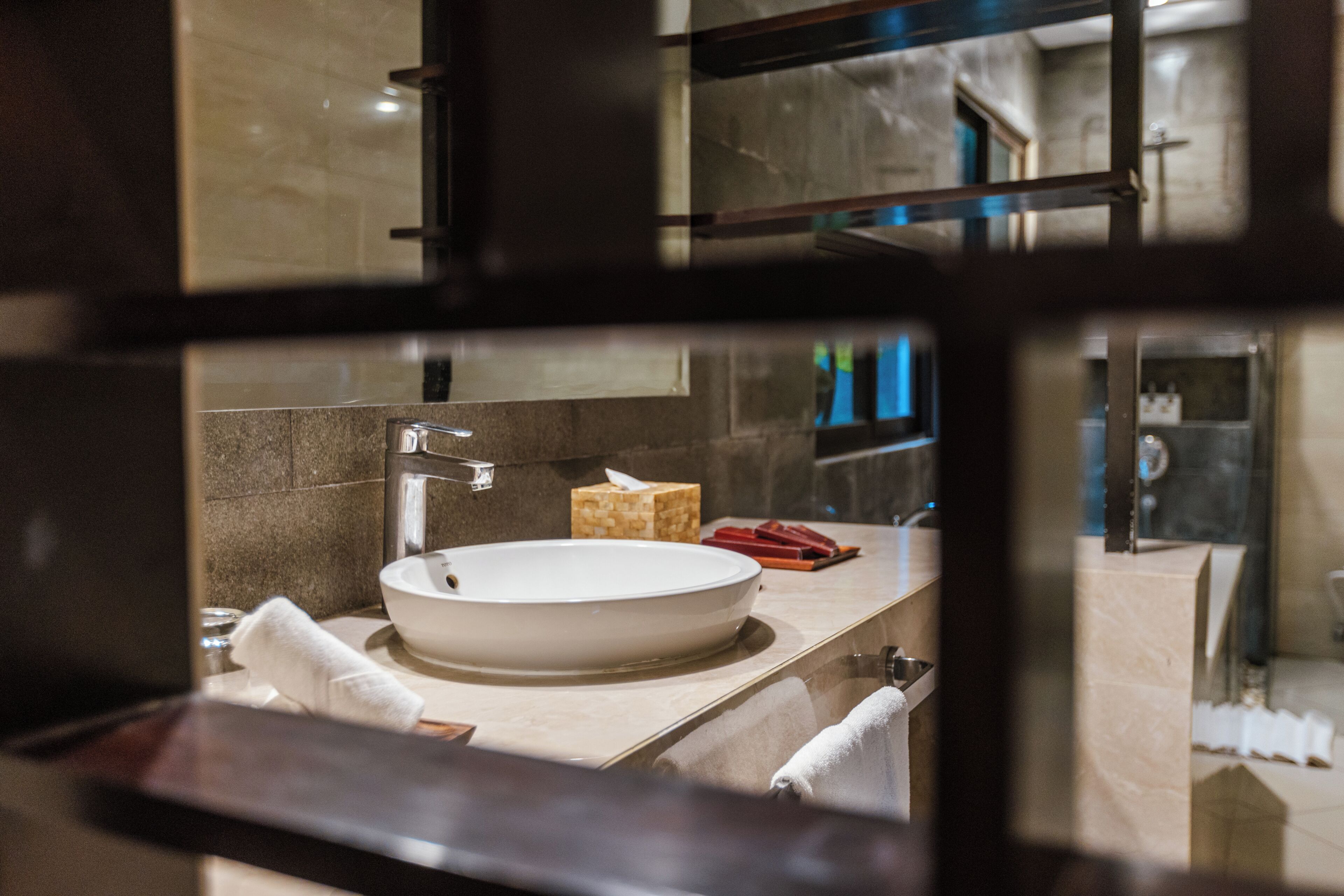 A modern bathroom with a round sink, a mirror, and a towel rack.