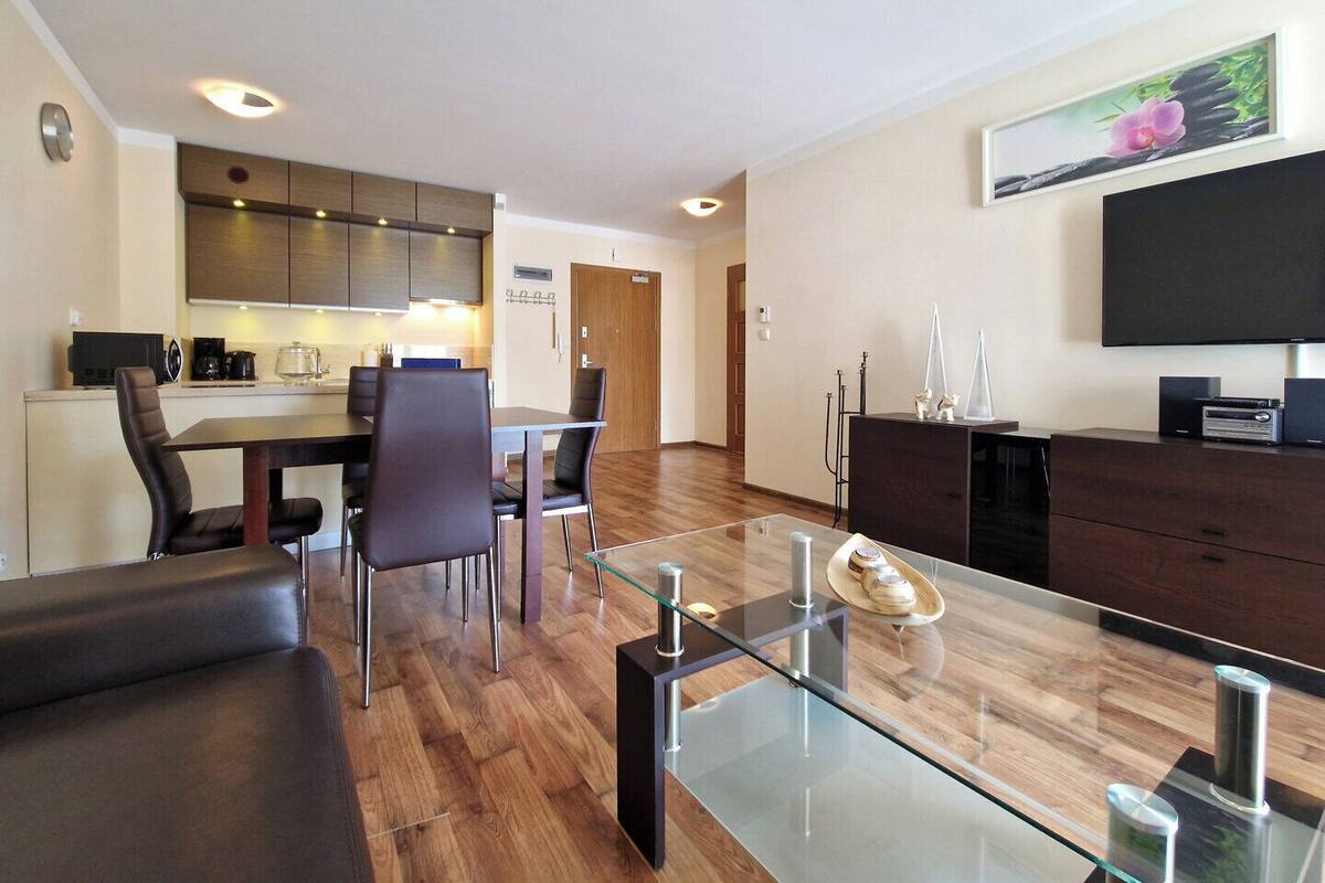 A modern living room with a glass coffee table, leather sofa, and a flat-screen TV.