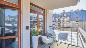 A balcony with a glass door, a potted plant, and two chairs. - Villa Mistral by Baltic Home (Swinoujscie)