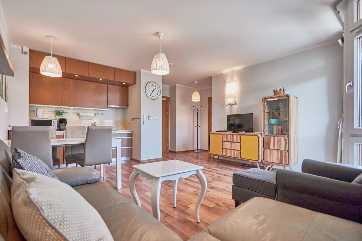 A modern apartment with a living room, dining area, and kitchen.