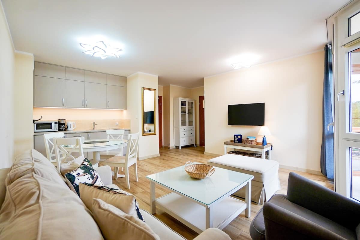 A modern living room with a glass coffee table, a sofa, and a television.
