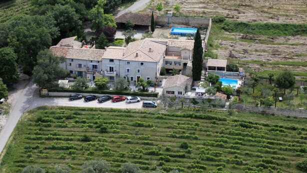 Un grand bâtiment à étages, entouré de vignobles en terrasses, et doté d’une piscine.