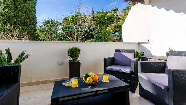 Ein Balkon mit Gartenmöbeln, einer Obstschale und zwei Gläser Orangensaft.