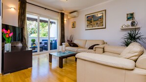Ein Wohnzimmer mit einer Couch, einem Couchtisch, einem Fernseher und einer Pflanze.