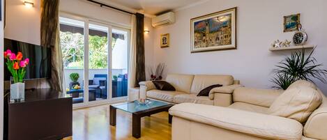A living room with a sofa, a coffee table, a TV, and a plant.