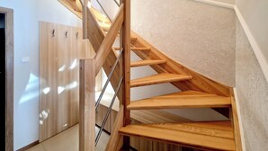 A wooden staircase with a metal handrail in a room with light-colored walls and a wooden wardrobe. - Holiday House by Baltic Home (Swinoujscie)
