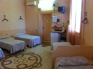 Une chambre d’hôtel avec deux lits simples, une petite kitchenette, un bureau et une télévision.