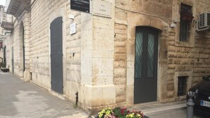 A stone building with a sign for 'Galleria di Fotografia Francesca Wedding Studio' and a large flower planter on the sidewalk. - B&B Casa Catalano (Terlizzi)
