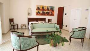 A bedroom with a bed, two chairs, a sofa, a potted plant, and a painting on the wall. - B&B Casa Catalano (Terlizzi)