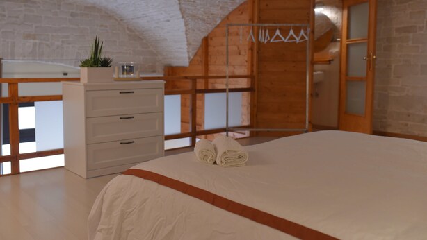A bedroom with a large bed, wooden wardrobe, and a small plant on the dresser. - B&B L' alcova (Terlizzi)
