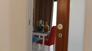 A room with a white door, a red chair, a blue chair, and two vases on a table. - B&B L' alcova (Terlizzi)