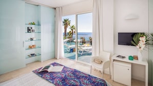 A hotel room with a bed, a desk, a TV, a chair, a bookshelf, and a view of the ocean. - Hotel Caravelle Thalasso & Wellness (Diano Marina)