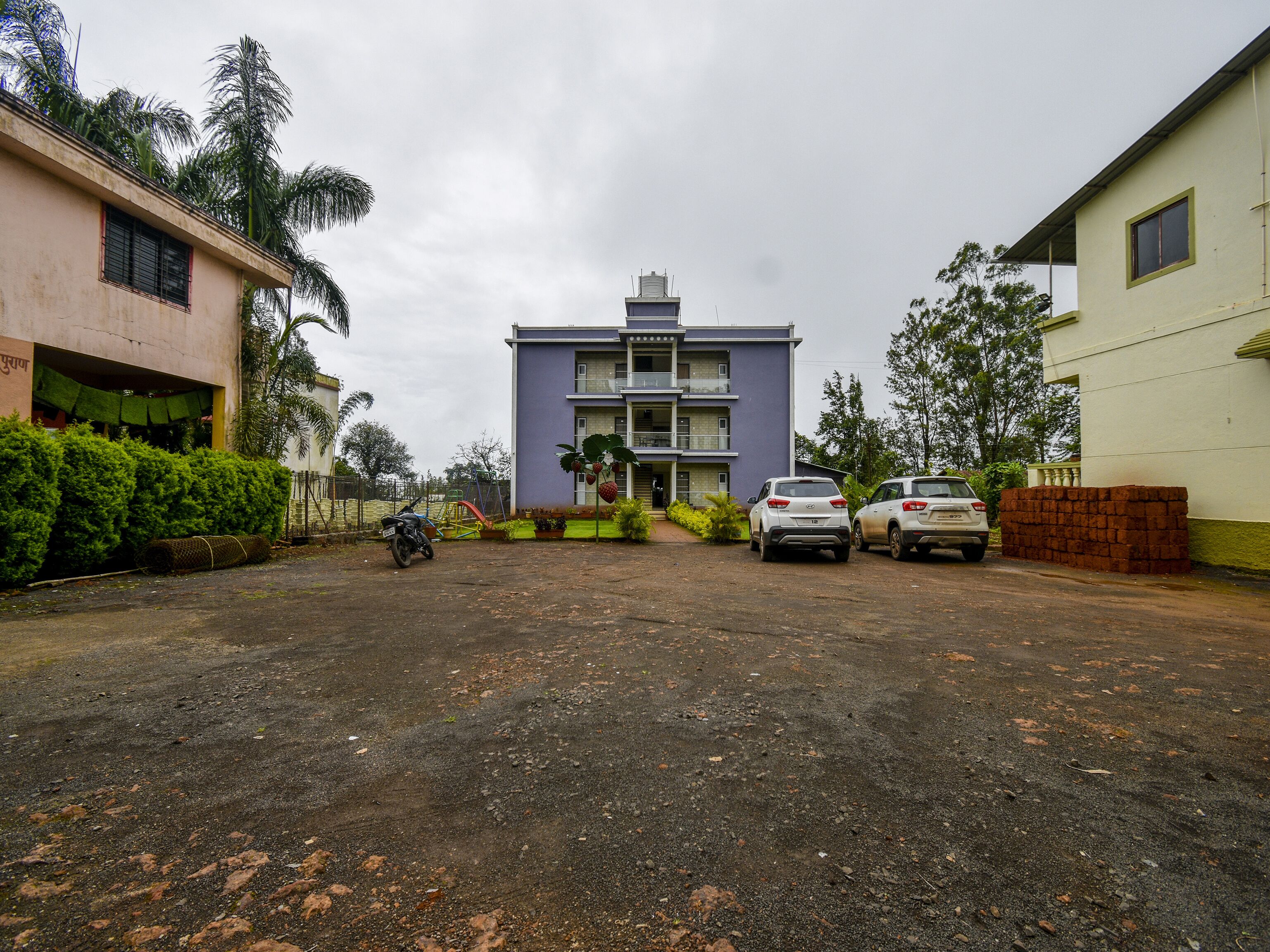 A residential area with a two-story building, parked cars, and a motorcycle.