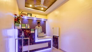A reception desk with a laptop, a ceiling fan, and a wooden ceiling. - Treebo Prince Palace With Swimming Pool (Mahabaleshwar)