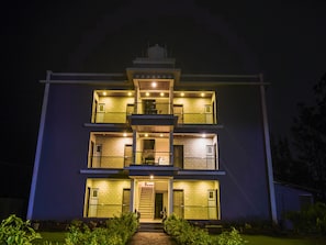A multi-story building with a central staircase, balconies, and a flat roof. - Treebo Prince Palace With Swimming Pool (Mahabaleshwar)