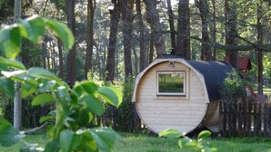 Uma pequena cabana de madeira com janela, cercada por árvores e um muro.