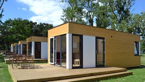 Uma cabana moderna de madeira com grandes portas de vidro e um deck.