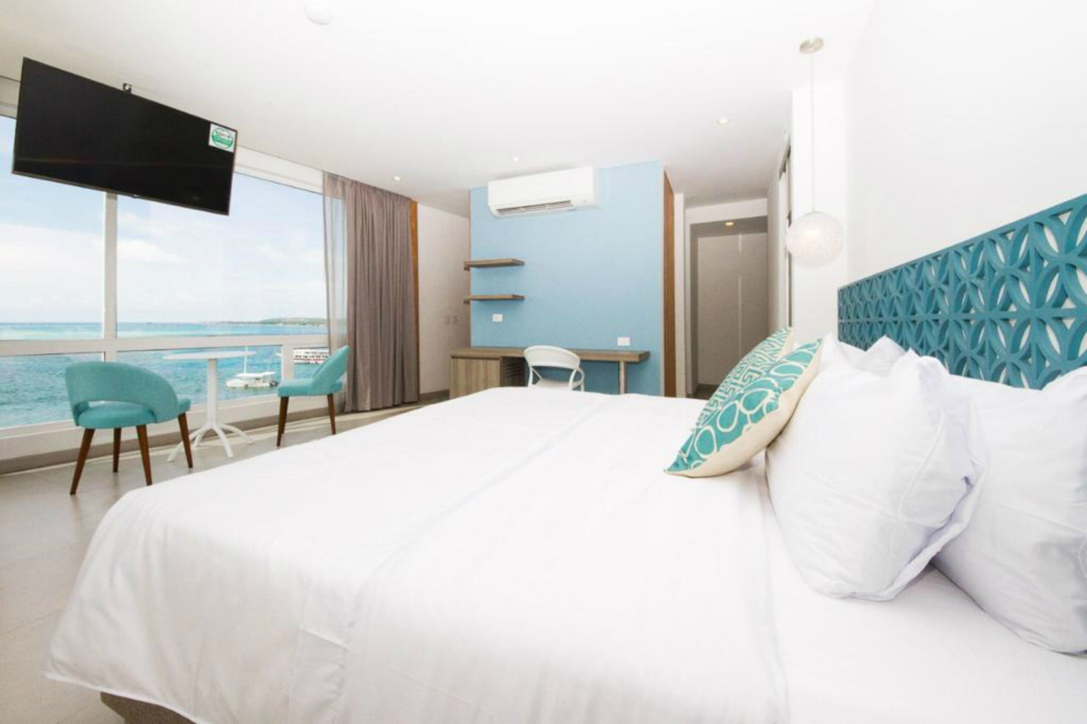 Una habitación de hotel con una cama grande, un escritorio, una silla y un televisor montado en la pared.