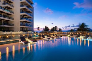 A poolside area with lounge chairs and a building with balconies. - Samawi (San Andrés)