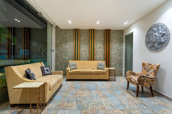 A modern living room with a beige sofa, patterned armchair, and decorative wall art. - Samawi (San Andrés)