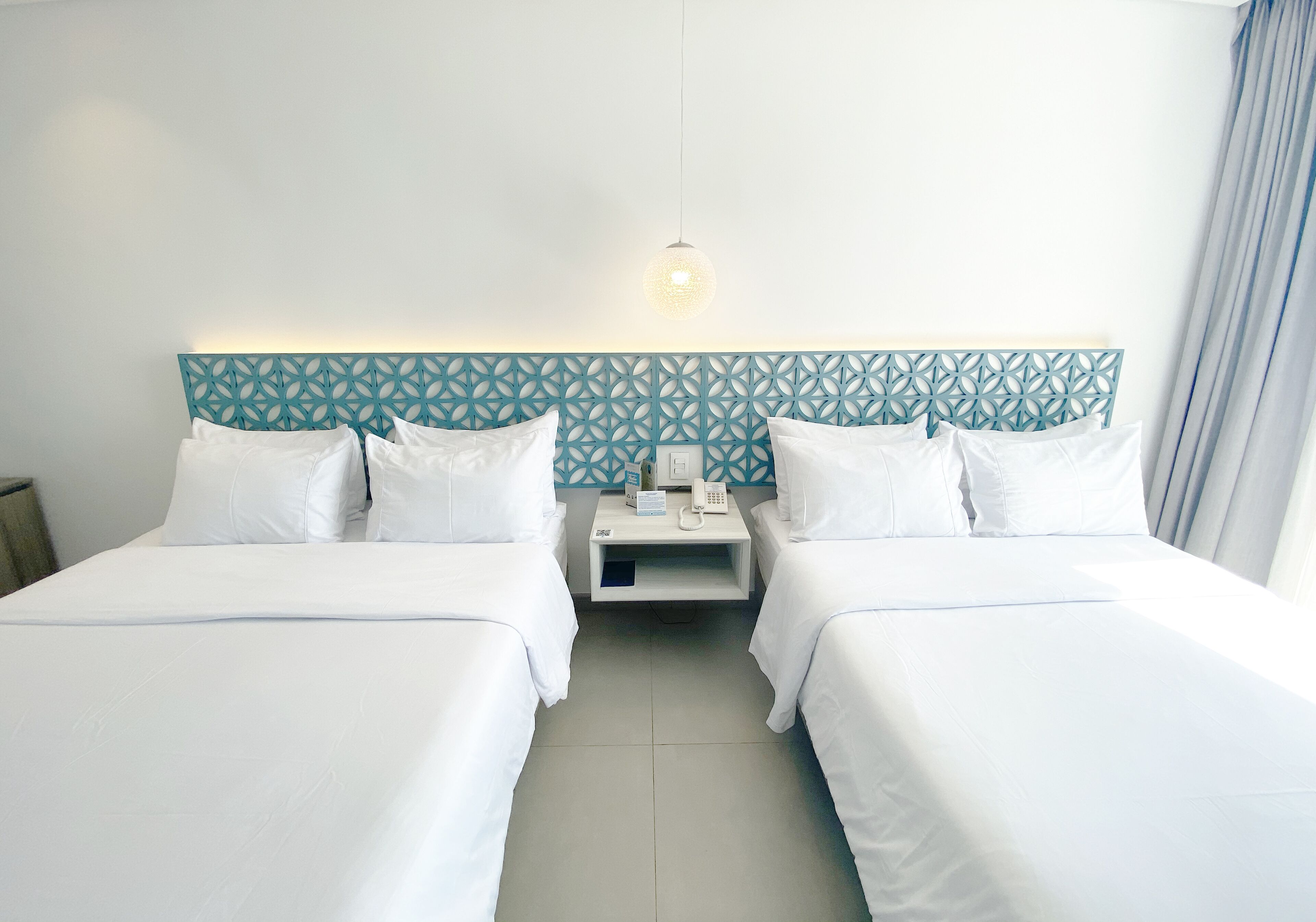 A hotel room with two beds, a nightstand, a telephone, and a decorative headboard.