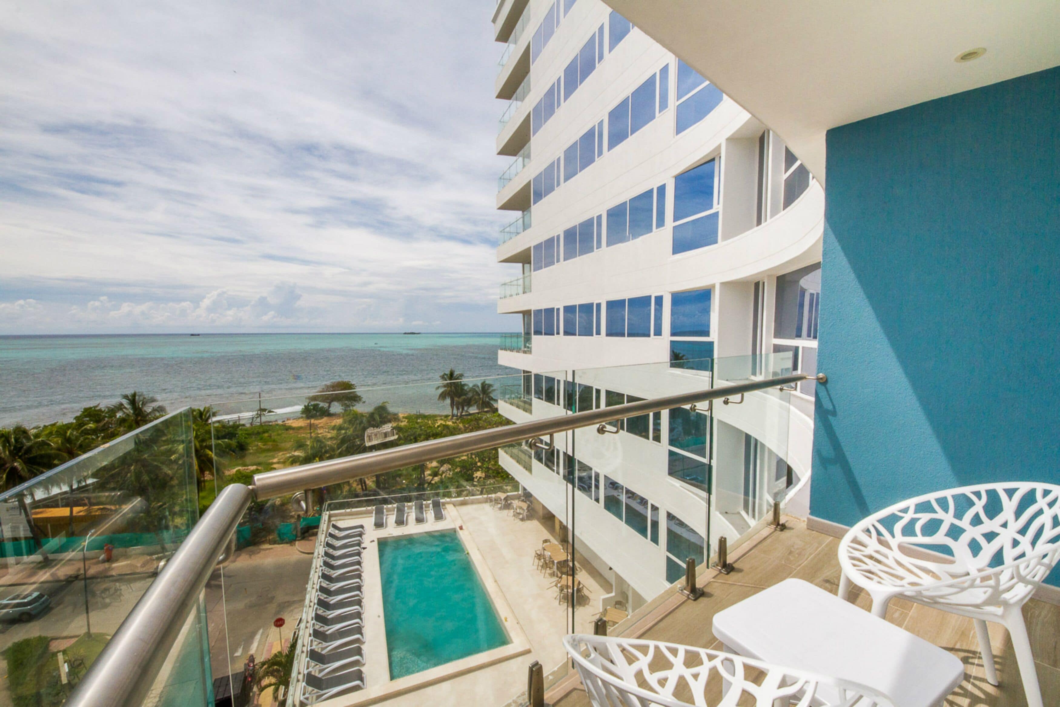 A hotel balcony with a pool, overlooking the ocean.