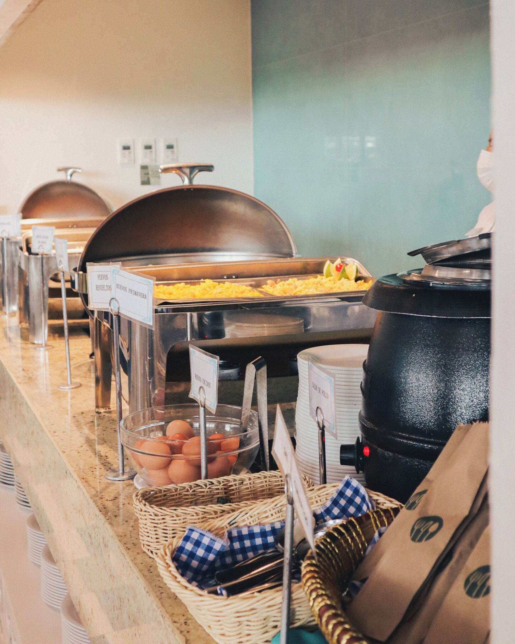 Ein Buffet mit beschrifteten Behältern für verschiedene Speisen, darunter Eier und ein Gericht mit der Aufschrift „HUEVOS REVueltos“.