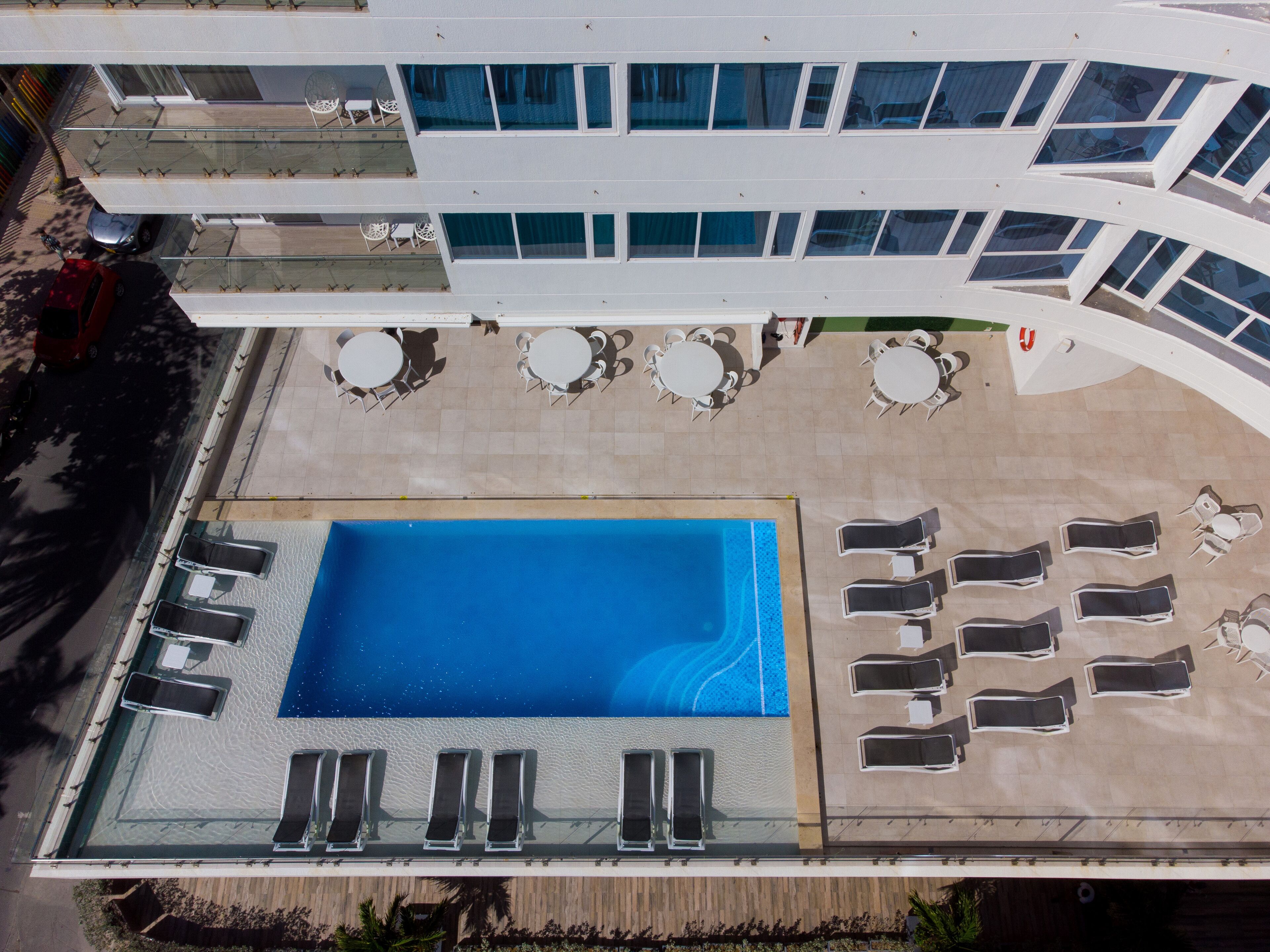 An aerial view of a hotel with a swimming pool, sun loungers, and outdoor seating areas.