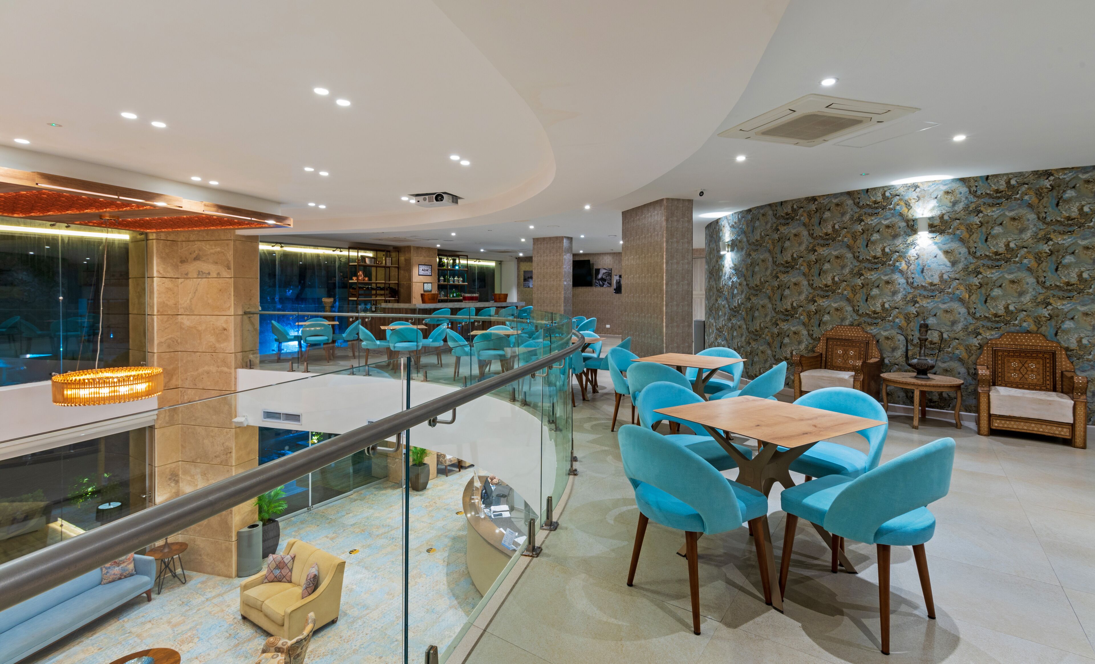 Eine moderne Hotelhalle mit Glastrennwand, Sitzgelegenheiten und einer Bar.