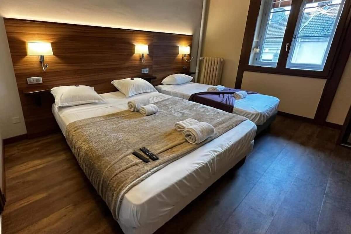 Ein Hotelzimmer mit zwei Betten, einem Holzkopfstück, Wandlampen und einem Fenster mit Blick.