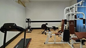 Un gimnasio con caminadora, elíptica y máquinas de pesas.