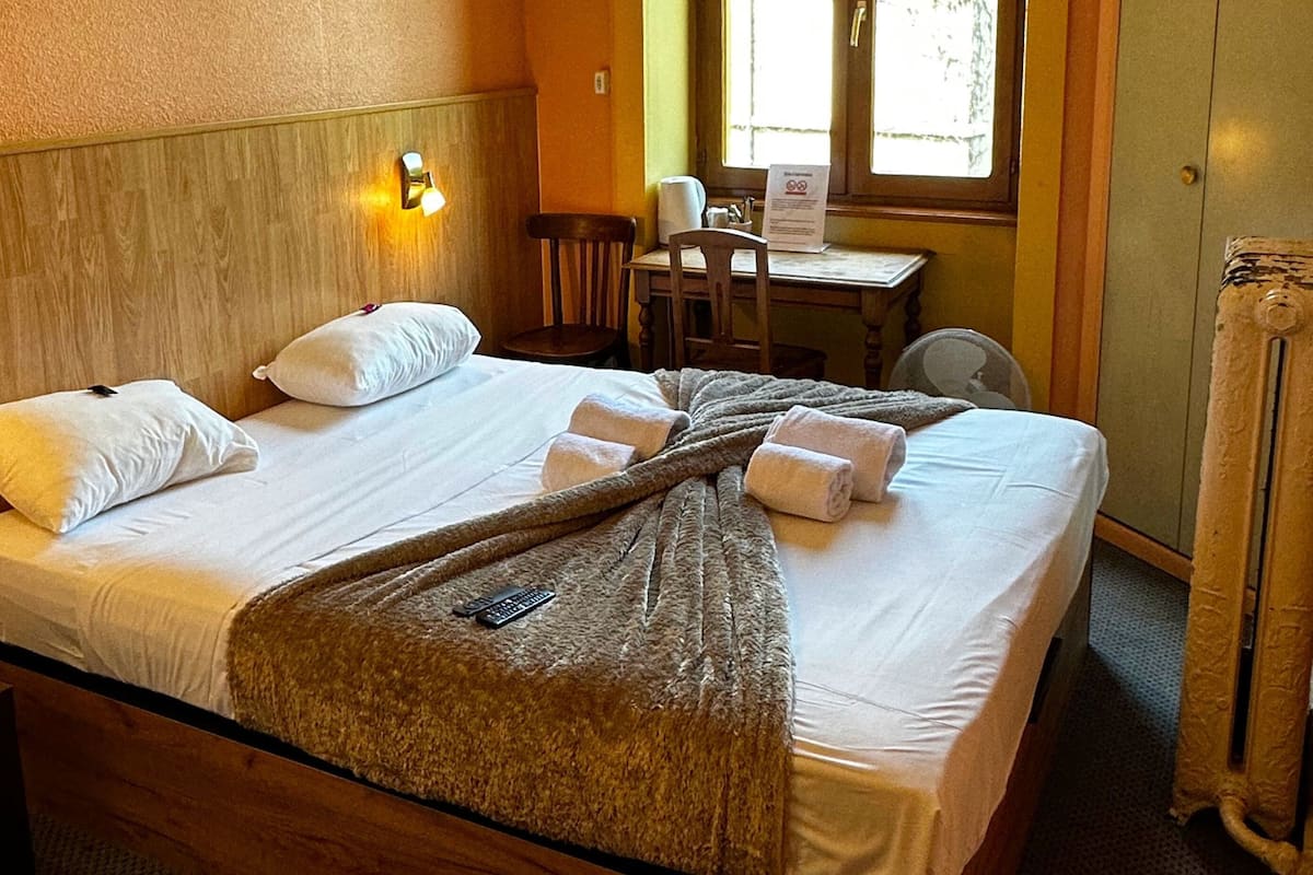 Ein Hotelzimmer mit einem großen Bett, einem Schreibtisch und einem Fenster.