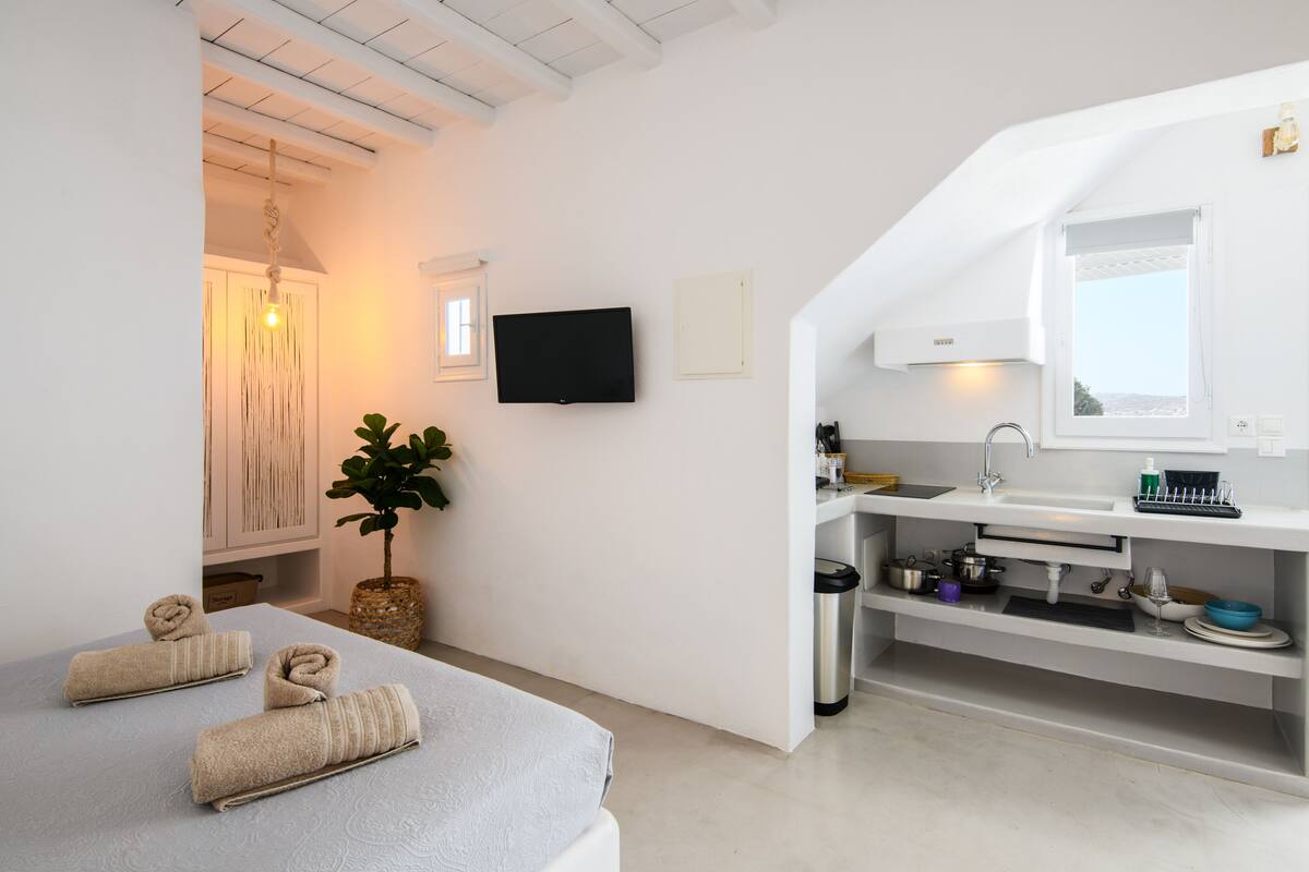 Une chambre d’hôtel moderne équipée d’un lit, d’une télévision, d’un lavabo et d’une petite fenêtre.