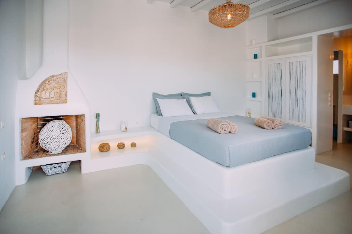 Une chambre moderne avec un grand lit, une cheminée intégrée et un panier en osier.