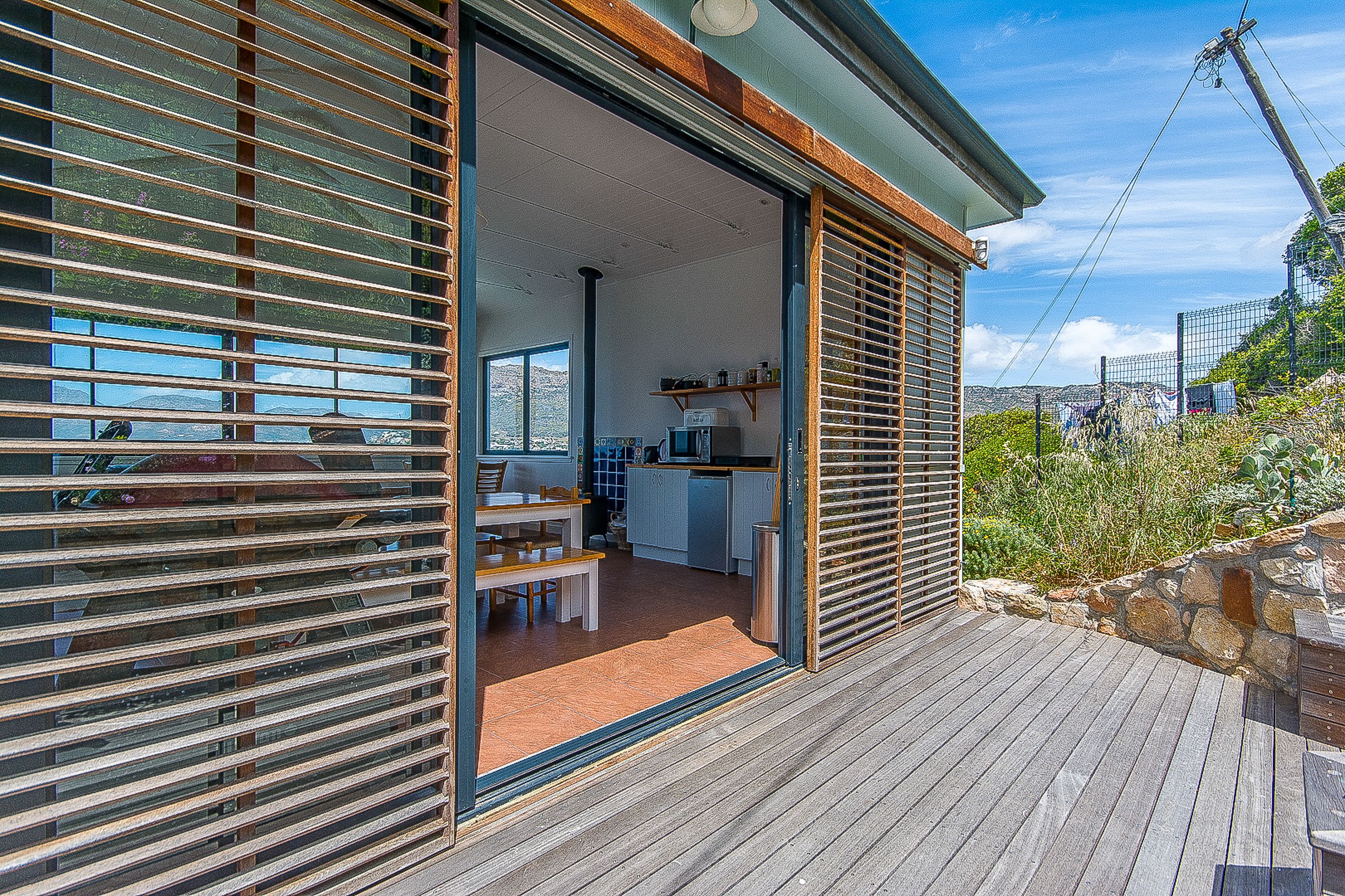 Uma casa moderna com deck de madeira, cozinha e área de jantar.