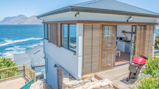 A coastal house with a deck, a barbecue grill, and a view of the ocean. - Modern Beach Appartment (Cape Town)