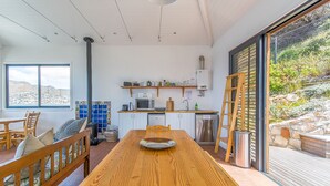 A kitchen with a wooden table, white cabinets, a microwave, and a stove. - Modern Beach Appartment (Cape Town)