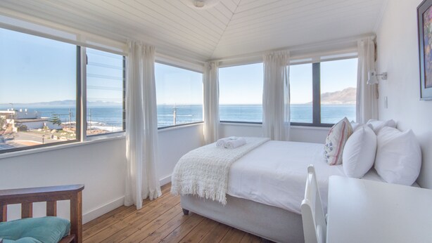 Een slaapkamer met een groot bed, een houten vloer en uitzicht op zee.