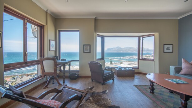 Amplio salón con gran vista al océano y las montañas, muebles de madera y alfombra de cuero.