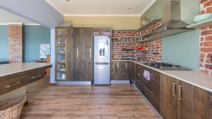 Una cocina moderna con armarios de madera, un refrigerador de acero inoxidable y una pared de ladrillo decorativa.